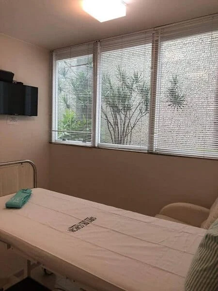 Quarto do Hospital Dia da Clínica Art Corporis, com poltrona de acompanhante e janela ampla.